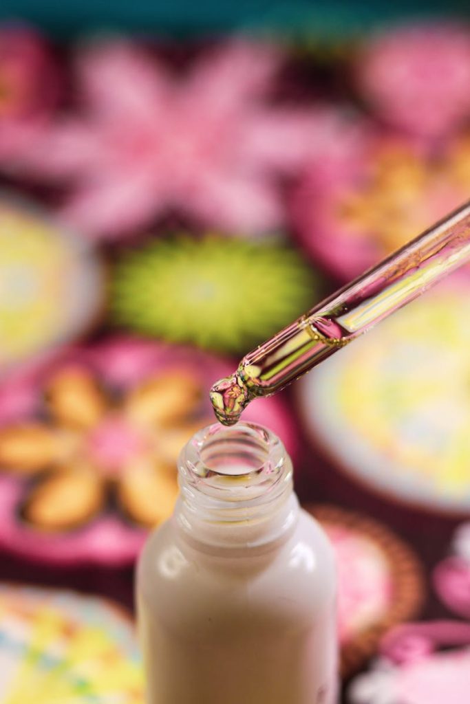 CBD oil dropper close-up with colorful floral background, showcasing product detail and beauty.