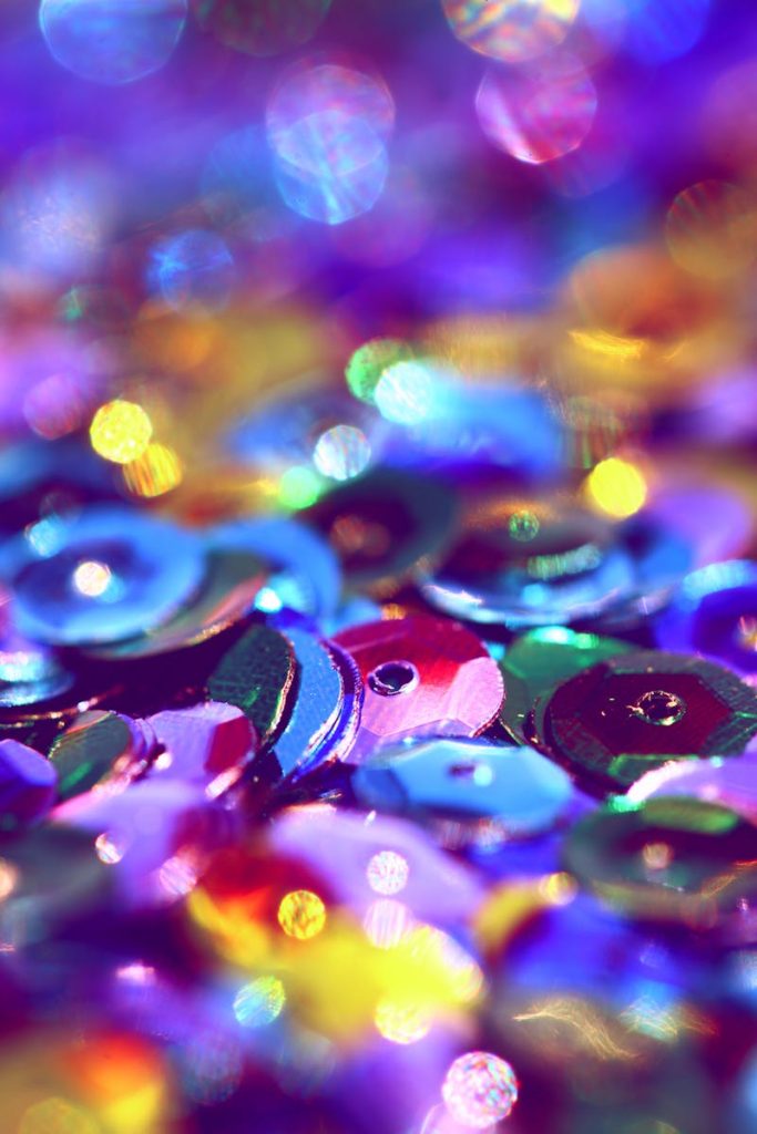 Vibrant macro shot of colorful sequins with a sparkling bokeh effect.