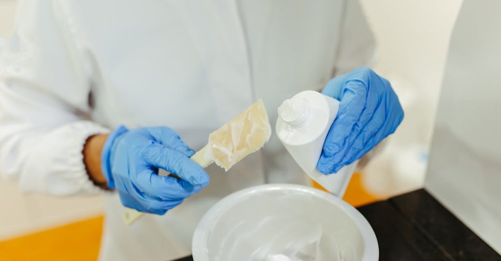 A lab technician wearing gloves mixes skincare cream with precision for research purposes.