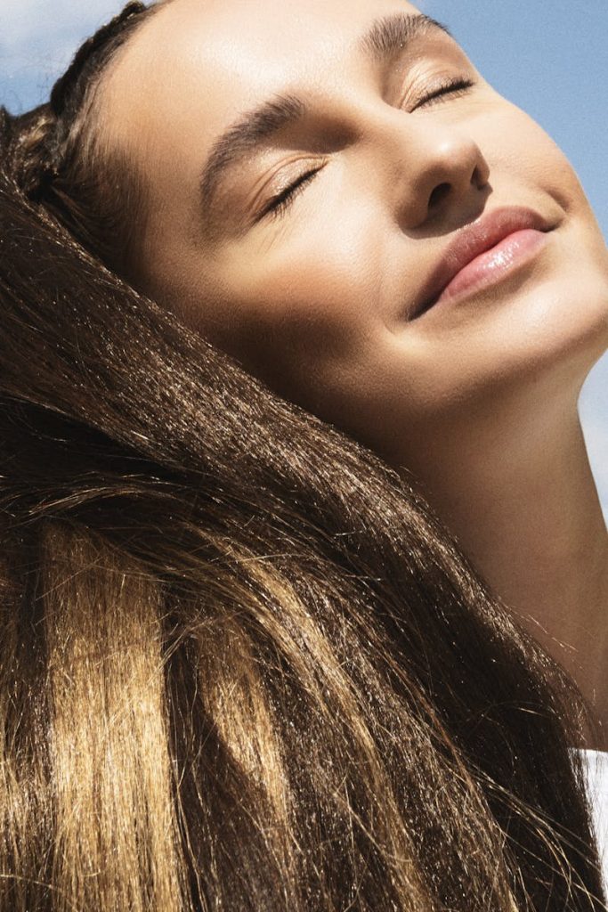 A serene portrait of a young woman with eyes closed, basking in warm sunlight.