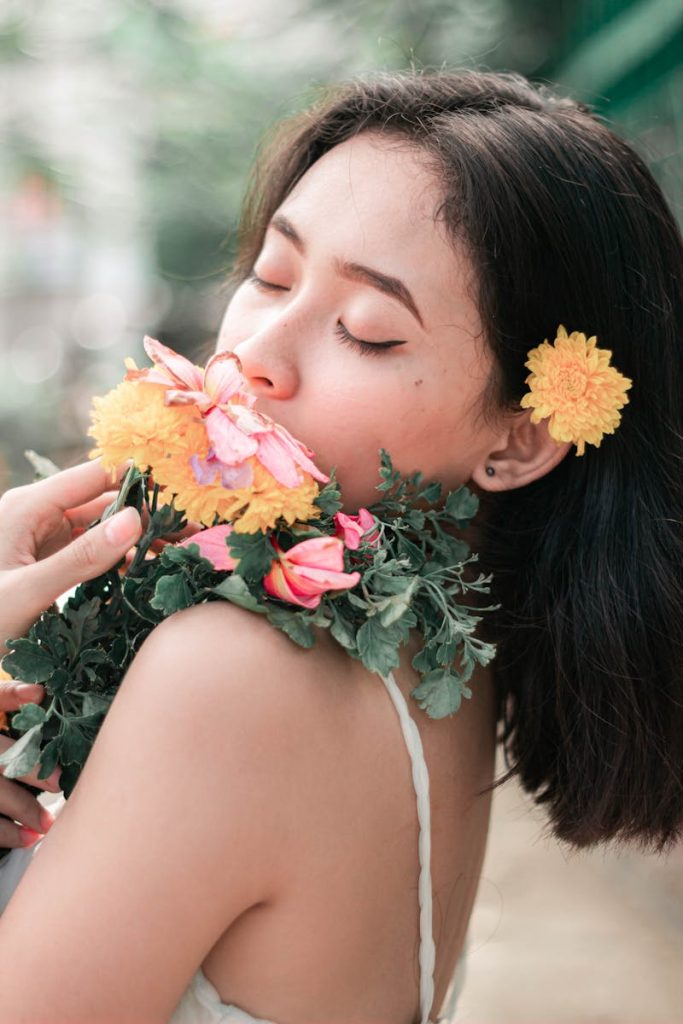 Elegant young woman enjoying fragrant flowers, expressing tranquility and natural beauty.