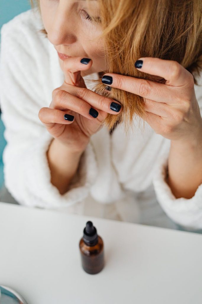 Close-up of a woman applying hair oil, focusing on hair care routines.
