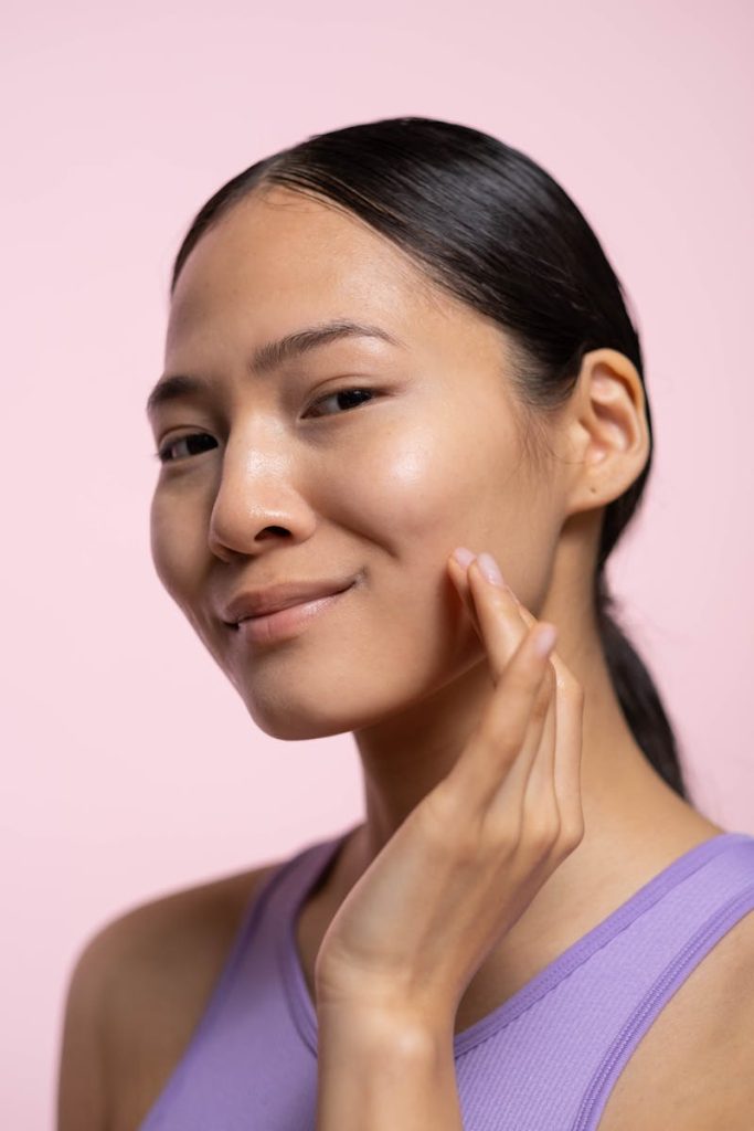 A close-up portrait of a smiling woman with healthy skin in a skincare studio setting.