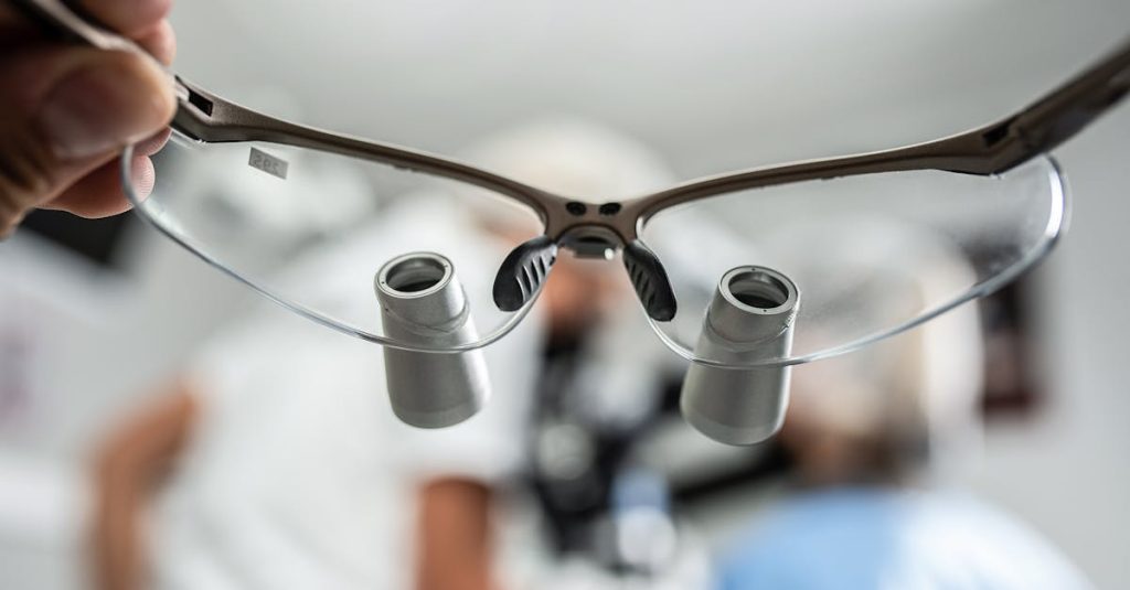 Close-up of dental loupes with blurred background, depicting a dentist at work.