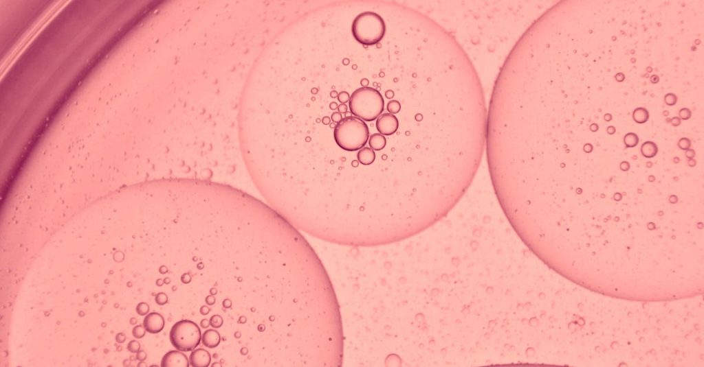 Stunning macro photo of pink oil bubbles in water, showcasing a microscopic view with intricate patterns.