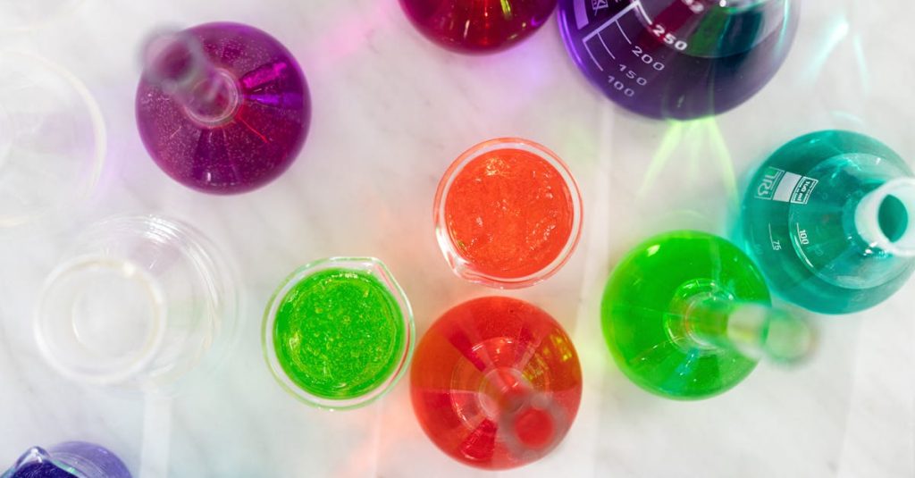 Aerial view of colorful liquids in laboratory glassware on marble surface, showcasing vibrant hues.